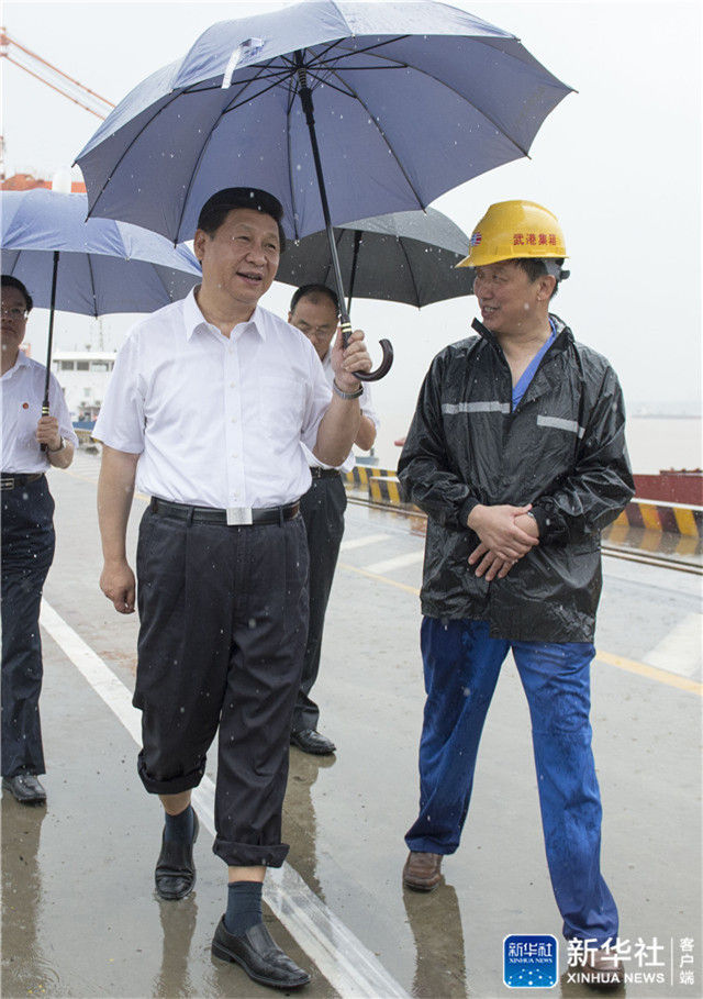 ↑2013年7月21日上午，習近平冒雨來到武漢新港陽邏集裝箱港區(qū)考察。記者 李學仁 攝